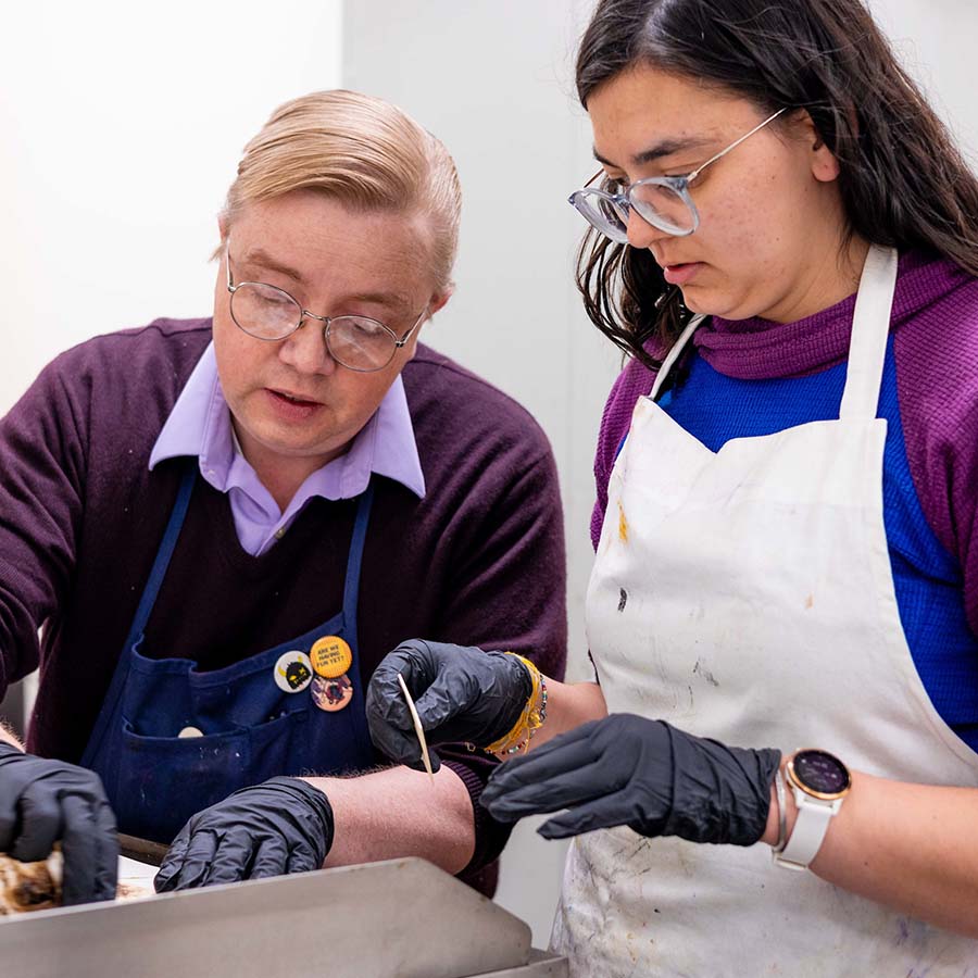 A student works with a professor on an art project